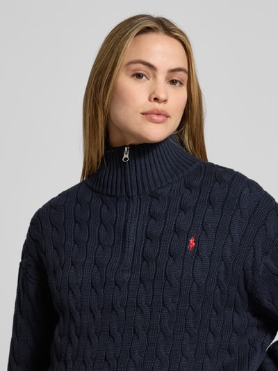 Vrouwenmodel draagt Troyer met kabelpatroon van Polo Ralph Lauren in donkerblauw, puur katoen, regular fit, logostitching, opstaande kraag met ritssluiting, elastische boorden, Nahaufnahme Oberkörper.