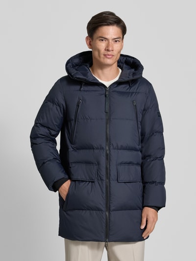 Männermodel trägt Regular Fit Daunenjacke mit Kapuze von Marc O'Polo in Dunkelblau, wasserabweisend, Pattentaschen, Ganzkörperansicht von vorne.
