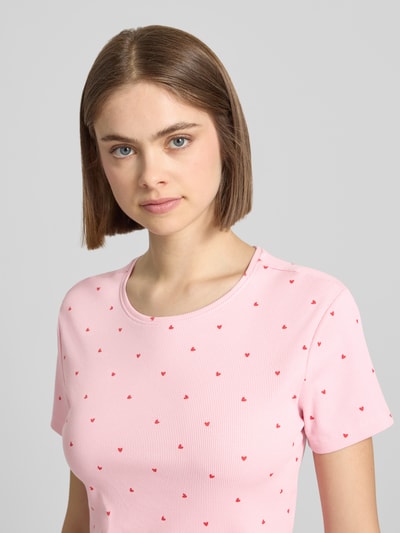 Frauenmodel trägt Regular Fit T-Shirt aus Baumwoll-Mix Modell 'FENJA' von Only, Optik: Allover-Muster, Motiv-Print, Feinripp, Farbe Rosa, Nahaufnahme Oberkörper.
