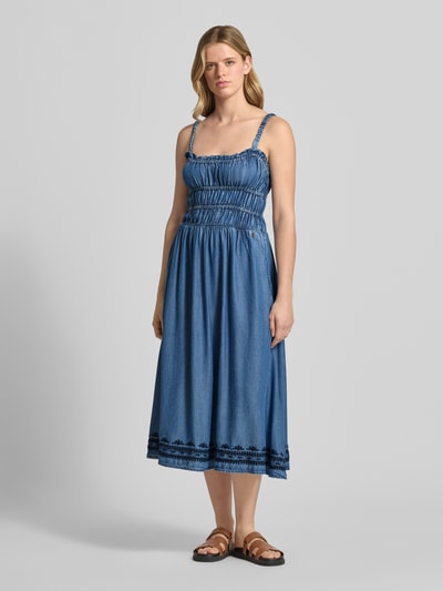 Vrouwenmodel draagt Tailliertes Jeanskleid aus Lyocell van Pepe Jeans in denimlook met getailleerd model, midilengte, vierkante hals, kwastdetails, borduursel, elastische borstbanden, naadritssluiting, tunnelkoord, smalle bandjes, materiaal lyocell. Volledige vooraanzicht.