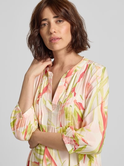 Frauenmodel trägt knielanges Tunikakleid mit V-Ausschnitt Modell 'Ma44gali' von ZABAIONE, Pastellfarben, florales Muster, reine Viskose, Nahaufnahme Oberkörper.