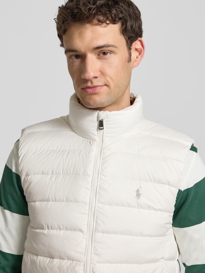 Mężczyzna model nosi Regular Fit Weste in Stepp-Optik od Polo Ralph Lauren, krój regular fit, stójka, zamek błyskawiczny, wyhaftowane logo, wpuszczane kieszenie, długość tyłu 69 cm, szerokość ramion 44 cm, szerokość klatki piersiowej 58 cm, jasny kolor, gładka tekstura, nahaufnahme górnej części ciała.