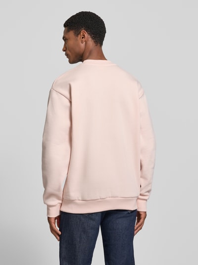 Männermodel trägt Regular Fit Sweatshirt aus Baumwoll-Mix von Lacoste in hellrosa mit weicher Textur, Ganzkörperansicht Rückansicht. Herren Sweatshirt.