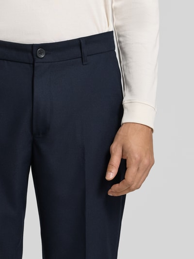 Męski model nosi Regular Fit Anzughose mit Bügelfalten von Les Deux, materiał z domieszką wełny, kolor granatowy, szerokość w rozmiarze 32: 44 cm, długość nogawki od kroku 78 cm, tylne kieszenie, detaliczne zbliżenie na górną część spodni