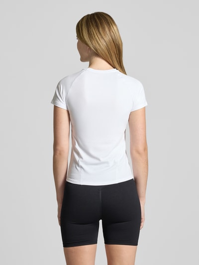 Modelka nosi T-Shirt mit Ziernähten od aim'n, biały, krój slim fit, półprzezroczysty materiał, okrągły dekolt, z dekoracyjnymi szwami, długość pleców w rozmiarze S: 55 cm, całkowity widok sylwetki od tyłu.