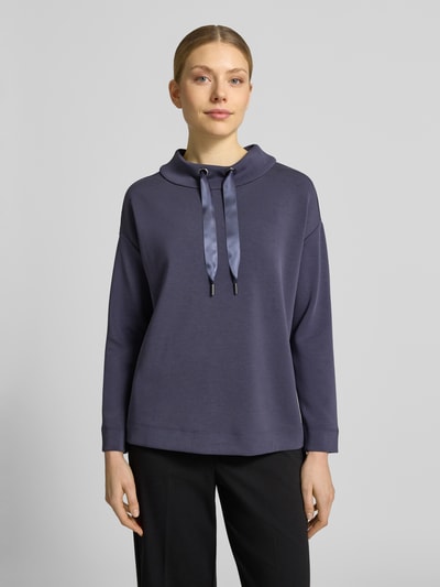 Frauenmodel trägt Loose Fit Sweatshirt aus Modal-Mix von s.Oliver BLACK LABEL, Optik: Unifarben, Passform: Loose-Fit, Logo-Detail, Kragenform: Mock Neck mit Tunnelzug, Langarm, Rumpfabschluss: leicht abgerundet, Material: Modal-Mix, glatte Struktur, dezente Farbe, Ganzkörperansicht von vorne.
