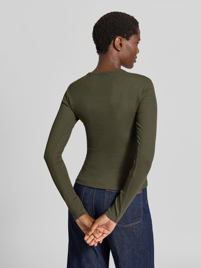 Frauenmodel trägt Slim Fit Langarmshirt aus Baumwoll-Mix Modell 'CHLOE' von VERO MODA in Olivgrün, glatte Textur, Ganzkörperansicht Rückansicht.