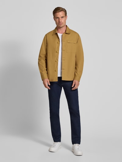 Męski model nosi Straight Fit Jeans aus Baumwoll-Mix von bugatti w kolorze granatowym, mieszanka bawełny, 5 kieszeni, zapięcie na guzik i zamek błyskawiczny, szerokość w rozmiarze 32/32: 43 cm, długość wewnętrzna nogawki w rozmiarze 32/32: 80 cm, widok całej sylwetki z przodu.