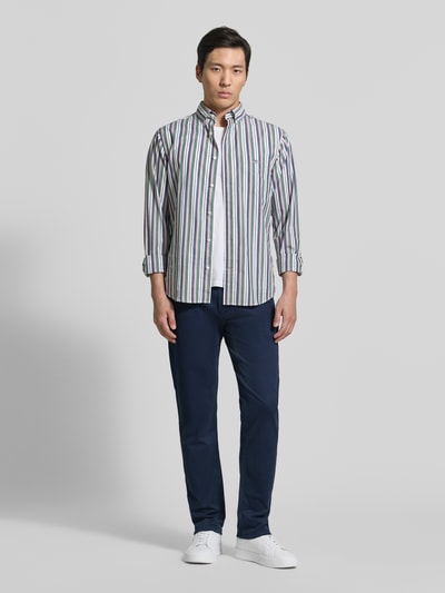Männermodel trägt Regular Fit Chino aus Baumwoll-Mix von s.Oliver RED LABEL, efekt: jednolity kolor, krój regular fit, średni stan, naszywka z logo, szlufki na pasek, zapięcie na guzik i zamek błyskawiczny, 5 kieszeni i ukryta kieszeń zapinana na zamek błyskawiczny, mieszanka bawełny, ganzkörperansicht von vorne
