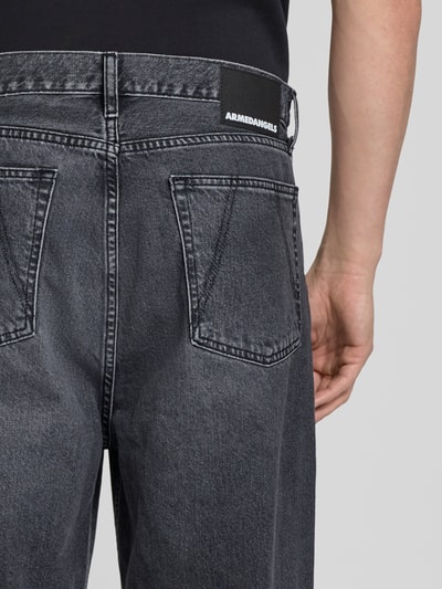 Männermodel trägt Loose Fit Baggy Jeans aus reiner Baumwolle Modell 'JAAMEO' von Armedangels in schwarzer Denim-Optik mit Label-Patch, 5-Pocket-Design und Gürtelschlaufen; Detailaufnahme Rückansicht.