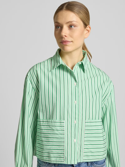 Vrouwenmodel draagt Loose Fit Langarmbluse aus reiner Baumwolle van s.Oliver RED LABEL, gestreept in groentinten, popeline stof, opgestikte zakken, korte lengte, volledig effen look, knoopsluiting, manchet, asymmetrische rompzoom, pure katoen kwaliteit, geheel van voren opgenomen, Nahaufnahme Oberkörper.
