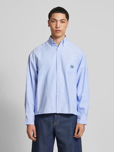 Męski model nosi Regular Fit Freizeithemd mit Motiv-Stitching od ANOTHER COTTON LAB, jasnoniebieski bawełniany krój regular fit, kieszeń na piersi, haft motywu, zapięcie na guziki, Button-Down-Kragen, label-detail, sportowe mankiety, długość tyłu w rozmiarze M: 71 cm, szerokość w rozmiarze M: 53 cm, długość rękawa w rozmiarze M: 62 cm, zdjęcie całej sylwetki z przodu