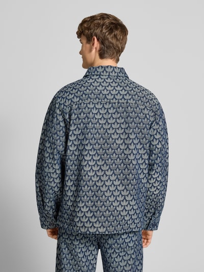 Męski model nosi Regular Fit Jacke in Denim-Optik Modell 'Monogram' od adidas Originals z niebieskiej bawełny, wzór monogram, całkowity widok z tyłu. Szerokość w rozmiarze M: 50 cm, długość pleców: 72 cm, szerokość klatki piersiowej: 59 cm, długość rękawa: 66 cm.