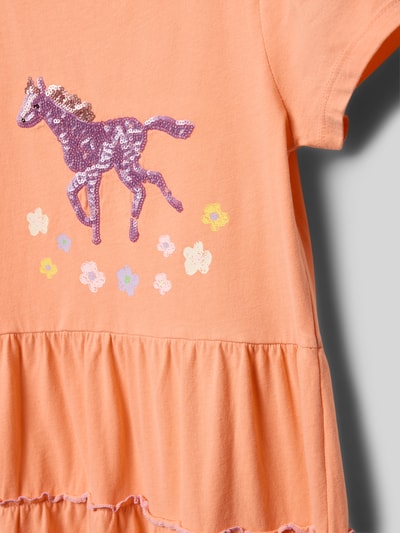 Dziewczynka nosi Tailliertes Freizeitkleid aus reiner Baumwolle od s.Oliver RED LABEL, efekt: jednolity kolor, nadruk z motywem, cekinowe obszycie, długość midi, okrągły dekolt, krótki rękaw, falbana na dole, wykończenie materiału: dżersej, materiał: bawełna, detal: kwiaty i fioletowy koń, widok: zbliżenie na górną część sukienki