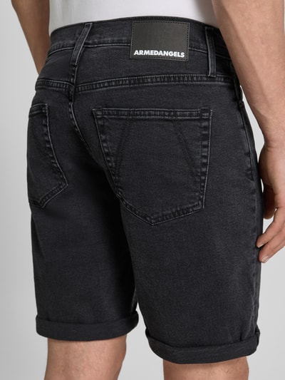 Männermodel trägt Slim Fit Jeansshorts aus Baumwoll-Mix Modell 'NAAILO' von Armedangels in Denim-Optik mit Label-Patch, 5-Pocket-Design, Beinabschluss mit Umschlag, Detailaufnahme Rückansicht.