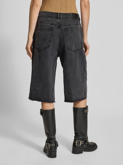Frauenmodel trägt Jeansshorts im Destroyed-Look von Karo Kauer, schwarze Farbe, entspannter Schnitt, Eingrifftaschen, Ganzkörperansicht Rückansicht.