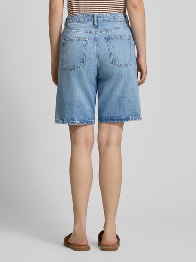 Frauenmodel trägt Regular Fit Jeansshorts aus reiner Baumwolle Modell 'SONNY' von Only, Denim-Optik, 5-Pocket-Design, Label-Patch, Nieten, Gürtelschlaufen, mittleres Blau, strukturierte Baumwoll-Oberfläche, Ganzkörperansicht Rückansicht.