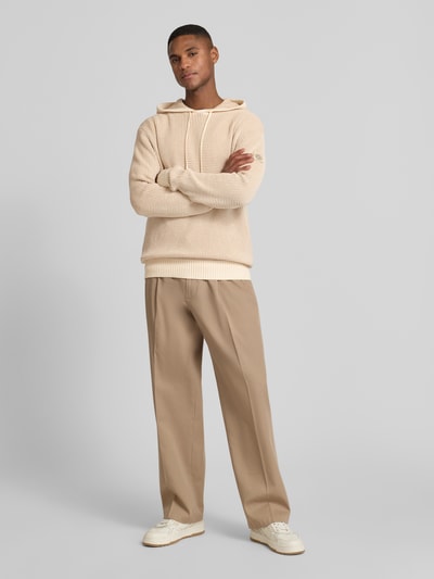 Männermodel trägt Slim Fit Hoodie mit Viskose-Anteil Modell 'Kem' von Guess, Strick-Optik in Beige, Baumwoll-Mix, Ganzkörperansicht von vorne