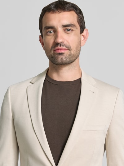 Männermodel trägt Slim Fit 2-Knopf-Sakko mit Paspeltaschen von MCNEAL, Viskose-Mix, cremefarben, Nahaufnahme Oberkörper.