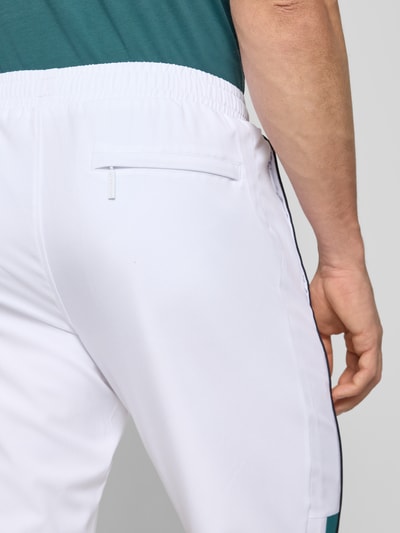 Männermodel trägt sweatpants mit logo-stitching Modell 'CASPIO' von SERGIO TACCHINI, wit, materiaalmix met stretch, steekzakken, nauwsluitend model, elastische band met trekkoord, detailaufnahme rechterheup.
