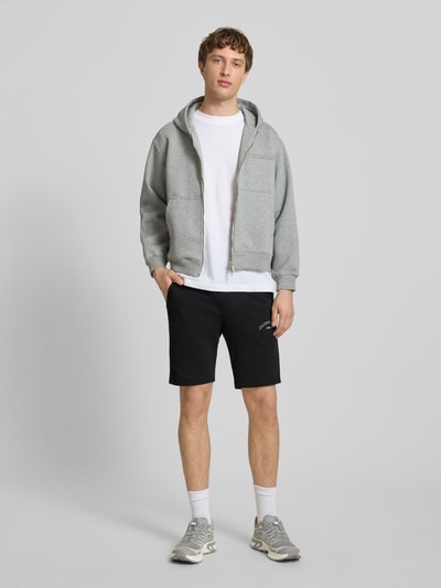 Männermodel trägt Shorts mit Logo-Print Modell 'GORDON' von Jack & Jones aus Baumwoll-Mix, Relaxed-Fit, Ganzkörperansicht von vorne.