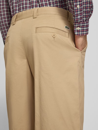 Männermodel trägt Loose Fit Weite Hose aus Baumwoll-Mix von Lacoste, beigefarbener Stoff, glatte Textur, Detailaufnahme Rückansicht, Herren Weite Hose von Lacoste.