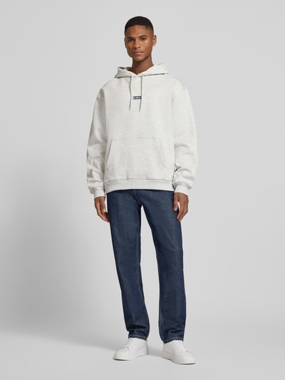 Männermodel trägt Hoodie mit Logo-Print Modell 'Chase' von Les Deux in Hellgrau, Loose-Fit aus Reine Baumwolle, Ganzkörperansicht von vorne.