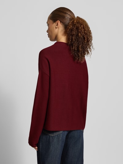 Frauenmodel trägt Loose Fit Pullover aus reiner Baumwolle Modell 'MERINAA' von ARMEDANGELS in Dunkelrot, strukturierte Oberfläche, Ganzkörperansicht Rückansicht.