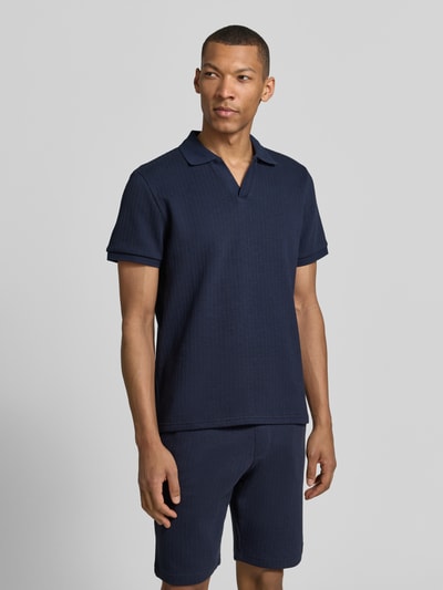 Männermodel trägt Regular Fit Strick-Poloshirt mit V-Ausschnitt von MCNEAL aus Baumwoll-Mix mit Stretch-Anteil in Dunkelblau, Ganzkörperansicht von vorne.
