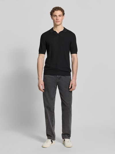 Männermodel trägt Slim Fit Poloshirt mit Viskose-Anteil von Roy Robson in Schwarz mit Strick-Optik, Strukturmuster und elastischen Abschlüssen, Rückenlänge bei Größe M: 67 cm, Ärmellänge 27 cm, Ganzkörperansicht von vorne.