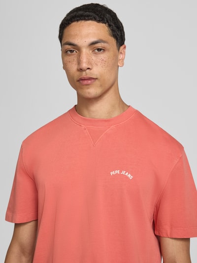 Männermodel trägt Regular Fit T-Shirt aus reiner Baumwolle Modell 'John Tee' von Pepe Jeans in Koralle, Herren T-Shirt, Nahaufnahme Oberkörper.