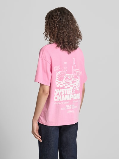 Frauenmodel trägt Oversized T-Shirt mit Logo-Print von ANOTHER COTTON LAB in Rosa, reine Baumwolle, lockerer Schnitt, Ganzkörperansicht Rückansicht