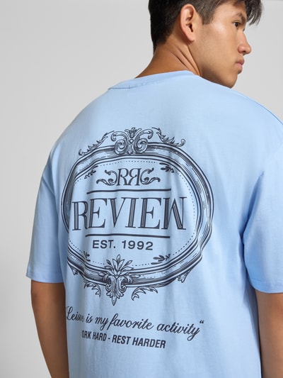 Männermodel trägt Regular Fit T-Shirt aus reiner Baumwolle mit rückseitigem Print von REVIEW, hellblau, Logo-Detail, Nahaufnahme Rückansicht.