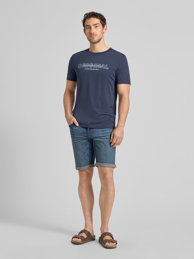 Męski model nosi Regular Fit T-Shirt aus reiner Baumwolle von Tom Tailor Denim, efekt: jednolity kolor, z napisem z logo, okrągły dekolt, krótki rękaw, 100% bawełna, Ganzkörperansicht von vorne.