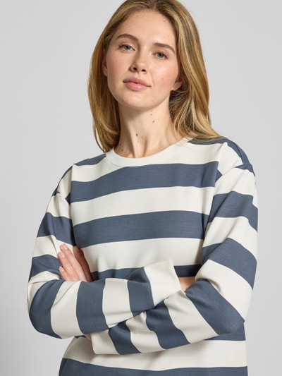 Modelka nosi bluzę 'Sweatshirt mit Rundhalsausschnitt' od Christian Berg Woman, mieszanka materiałów z domieszką modalu, krój relaxed fit, okrągły dekolt, wzór na całej powierzchni, niebiesko-białe szerokie paski, gładka tekstura, ujęcie z przodu do pasa