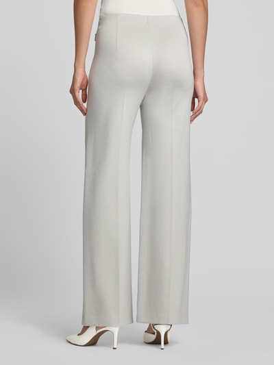 Frauenmodel trägt Hose aus Viskose-Mix mit Reißverschlusstaschen von Marc Cain in Hellgrau mit Bügelfalten, Regular-Fit, Ganzkörperansicht Rückansicht.