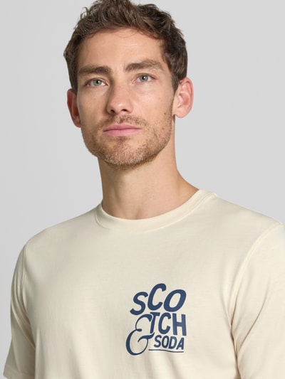 Männermodel trägt Regular Fit T-Shirt mit Logo-Print van Scotch & Soda in crème met donkerblau, Puur katoen, ronde hals, Nahaufnahme Oberkörper