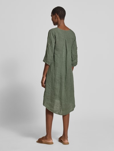 Frauenmodel trägt knielanges Leinenkleid mit Zierknopf Modell 'Ad44ora' von ZABAIONE, linia a, dekolt w serek, rękaw o dł. 3/4, długość do kolan, len, długość tyłu w rozmiarze S: 107 cm, szerokość w rozmiarze S: 47 cm, długość rękawów w rozmiarze S: 30 cm, gładka faktura, oliwkowy kolor, ganzkörperansicht rückansicht