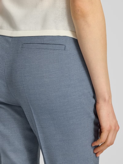 Frauenmodel trägt Hose mit Bügelfalten und Gesäßtasche von comma, Material-Mix mit Viskose-Anteil, feine Struktur, Nahaufnahme Rückansicht.