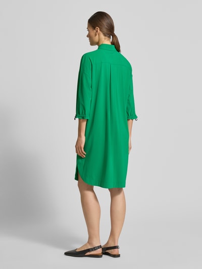 Männermodel trägt knielanges Hemdblusenkleid mit Knopfleiste von Marc Cain, zielony kolor, prosty krój, długość do kolan, całkowita tylna perspektywa.