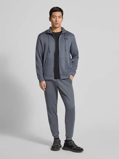 Męski model nosi Sweatpants mit elastischem Bund od Under Armour, luźny krój, kieszenie boczne, odcień szarości, widok całej sylwetki z przodu.