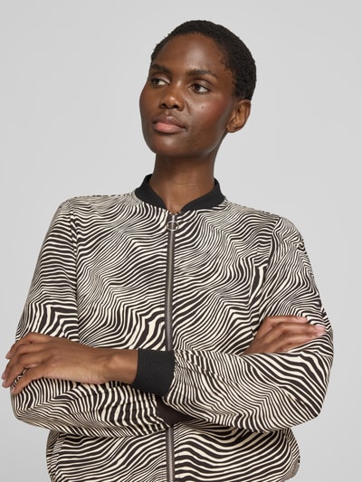 Frauenmodel trägt Regular Fit Blouson mit Allover-Muster Modell 'COCO' von VERO MODA, beige-schwarz, Nahaufnahme Oberkörper.