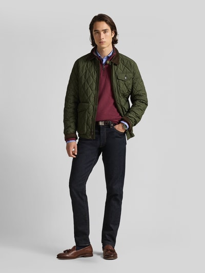 Männermodel trägt Regular Fit Sweatshirt aus Baumwoll-Mix von Polo Ralph Lauren in Dunkelrot, kombiniert mit grüner Jacke und Jeans, Ganzkörperansicht von vorne.