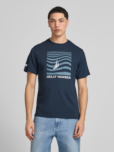 Männermodel trägt Herren T-Shirt mit Logo-Motiv-Print Modell 'SHORELINE' von Helly Hansen in Dunkelblau, Reine Baumwolle, Gerader-Schnitt, Ganzkörperansicht von vorne.