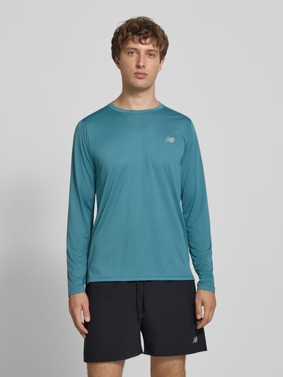 Männermodel trägt Funktionsshirt mit Rundhalsausschnitt und Logo von New Balance in Regular Fit, Longsleeve, blaue Farbe, Ganzkörperansicht von vorne.