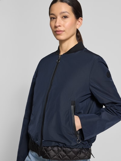 Vrouwenmodel draagt Jacke mit Stehkragen und Reißverschlusstaschen van Gil Bret in donkerblauw, regular fit, zichtbare ritssluiting en ritszakken, details uit context, close-up bovenlichaam vooraan.