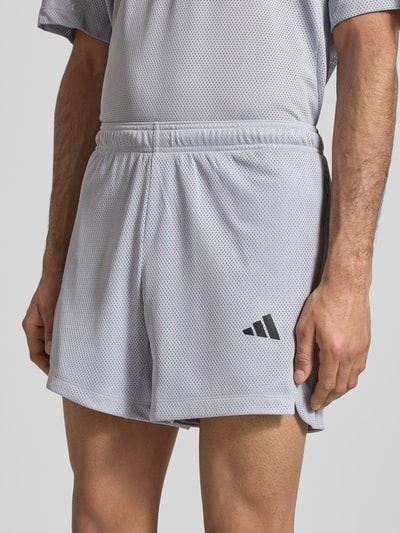 Männermodel trägt Shorts mit Label-Print von adidas Training in Hellgrau mit Lockerer-Schnitt und Elastischer-Bund, Nahaufnahme Oberkörper.