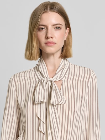 Frauenmodel trägt Slim Fit Schluppenbluse aus Viskose von Comma mit braunen Streifen, Teilungsnaht, Sportmanschetten, Nahaufnahme Oberkörper. Rückenlänge bei Größe 36: 64 cm, Ärmellänge 63 cm.