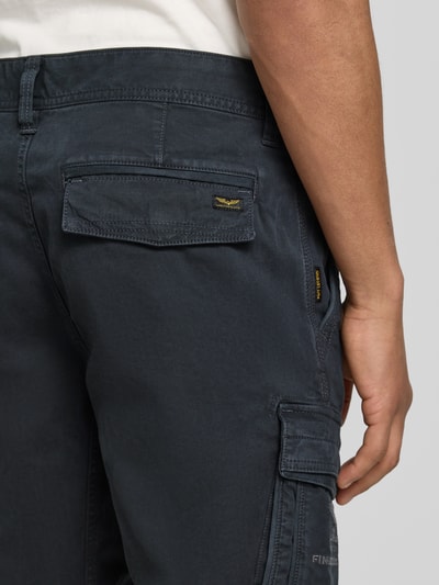 Männermodel trägt Bermudas mit Pattentaschen und Label-Stitchings von PME Legend in Dunkelblau, Motiv- und Label-Stitchings, Detailaufnahme Gesäßtasche, Straight Fit, Knopf- und Reißverschluss, seitliche Eingrifftaschen, Pattentaschen mit Klettverschluss, Label-Details, Bundweite bei Größe 32: 41 cm, Innenbeinlänge bei Größe 32: 26 cm.