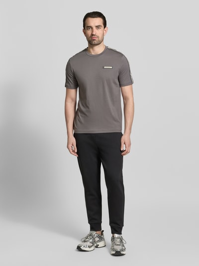 Męski model trägt Regular Fit T-Shirt mit Logo-Patch von EA7 Emporio Armani, bawełna, okrągły dekolt, długość tyłu 52 cm, Ganzkörperansicht von vorne